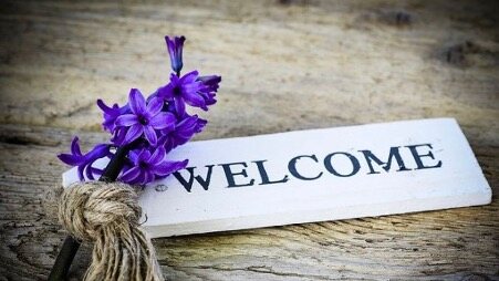 Hand-lettered WELCOME sign with purple hyacinth flowers resting on weathered wood